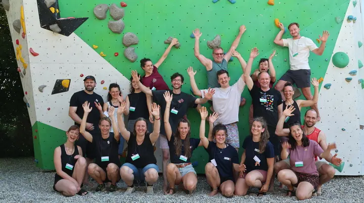 Die Teilnehmerinnen und Teilnehmer des Netzwerktreffens von "Seilschafft Inklusion!" stehen vor einer Kletterwand im Außenbereich der DAV Sektion Freiburg-Breisgau und strecken gut gelaunt die Hände in die Höhe | © Allpinistas + IWDR